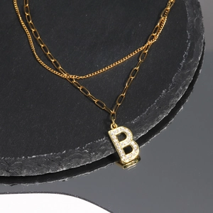 Detailed view of layered gold necklace with cubic zirconia paved letter B pendant
