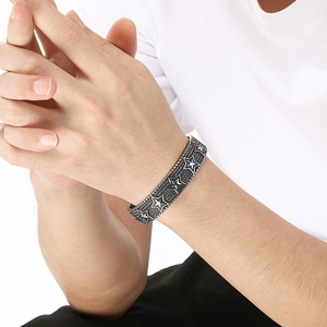 Detail of vintage silver cuff bracelet with embossed pentagram stars on a male wrist