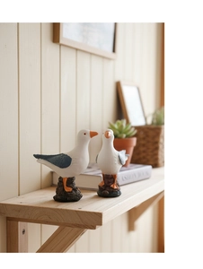 Detail of Nordic style resin seagull figurines on a wooden shelf with home decor