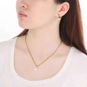 Detail view of pink strawberry pendant necklace and matching stud earrings set on model