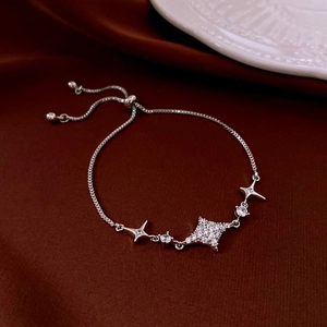 Dettaglio del bracciale regolabile a stella con zirconi su sfondo di seta