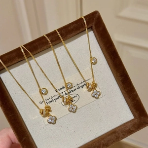 Detail of a gold clover necklace with a sparkling diamond pendant in a luxury gift box