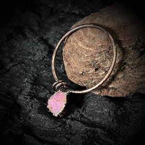 Dettaglio di un ciondolo in cristallo rosa grezzo con finitura bronzo e texture rustica