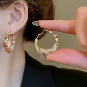 Golden twisted hoop earrings with sparkling cubic zirconia in a spiral mesh design
