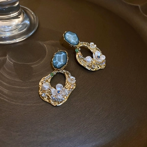 Vue détaillée des boucles d'oreilles dorées avec pierres bleues et fleurs blanches