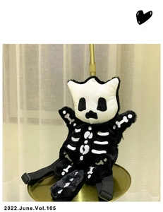 Detalle de bolso de hombro de peluche de gato esqueleto blanco y negro en soporte