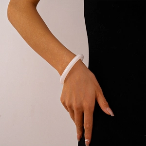Close-up of a translucent white acrylic bangle with agate texture on a model's wrist