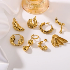 Minimalist gold titanium steel earring set with moon and spiral designs on white silk