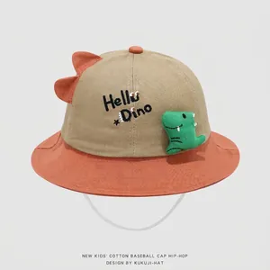 Detail of baby sun hat featuring Hello Dino embroidery and green plush dinosaur ornament