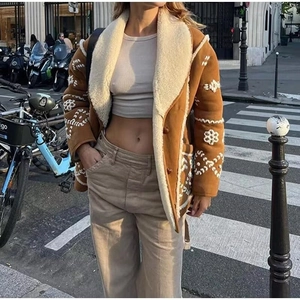 Brown faux shearling jacket with white embroidery and fur lining in street style