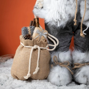 Figurine de Père Noël nordique blanc avec bottes en fourrure et sac sur neige feinte