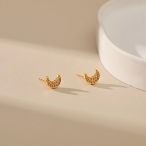 Close-up of gold-plated crescent moon earrings with shimmering zircon inlay detail