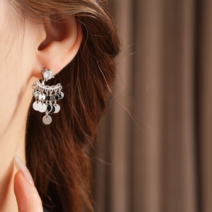 Close-up of silver tassel earrings with round zircon studs worn by a model