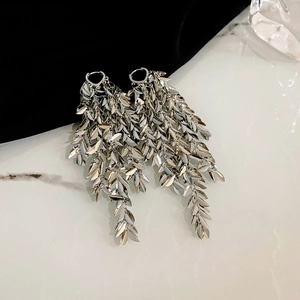 Close-up of silver leaf tassel earrings showing layered metal texture on black velvet