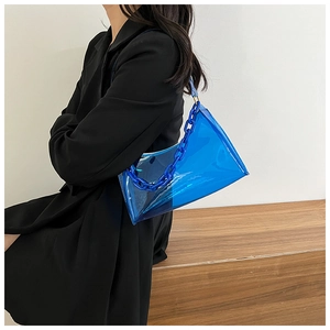 Detail of blue transparent PVC shoulder bag with chunky chain strap on a model