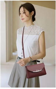 Detail of wine red PU leather crossbody bag featuring a curved silver metal buckle