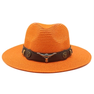 Detail of orange woven straw cowboy hat with brown leather band and silver bull head