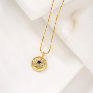 Détail macro du pendentif soleil doré avec pierre bleue centrale et zircons brillants