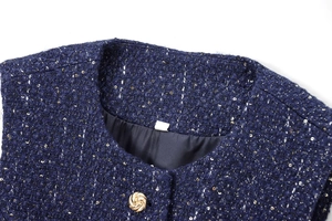 Macro shot of dark blue sequined tweed fabric with a golden vortex pattern metal button