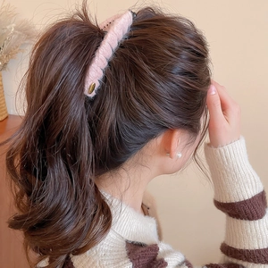 Détail d'une pince banane en tricot rose portée sur des cheveux bouclés de mannequin