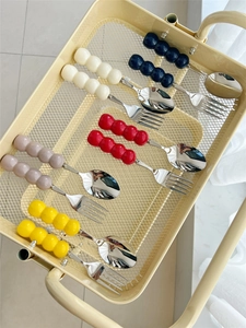 Detailed view of colorful ceramic bead handle cutlery sets displayed on a metal grid tray