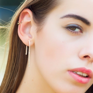 Macro view of gold tassel earrings with white zircon accents on female model