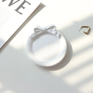 Close-up of a white bow plaster tray for jewelry display with elegant soft shadows