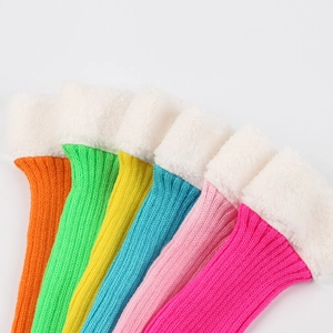 Close-up of six colorful knitted leg warmers with white faux fur trim on white background