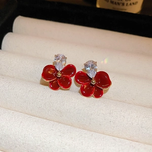 Detail of red flower earrings with gold borders and teardrop zircons in a jewelry box