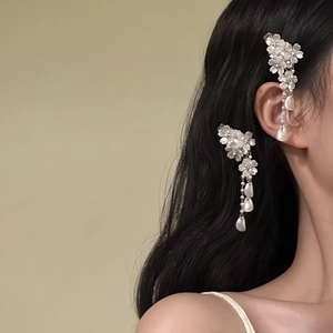 Close-up detail view of elegant white flower hair clip with tassels on model's hair.