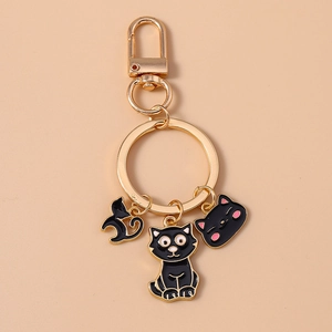 Creative black enamel cat keychain with golden metal ring on soft pink background