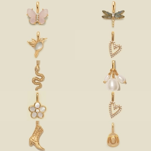 Golden butterfly and heart charm necklaces with pearls and gemstones on beige background