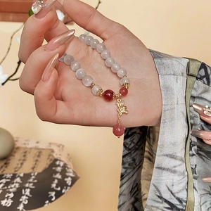 Macro detail of Chinese style beaded bracelet with cat eye stones and gold metal charms