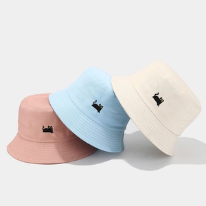 Three cotton bucket hats in pastel pink, blue, and white with black cat embroidery details