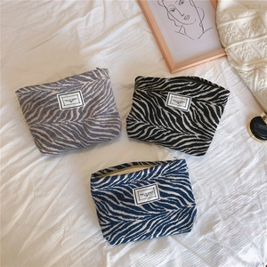 Detailed top view of three zebra-pattern canvas makeup bags with 'TIME TO PARTY' woven labels