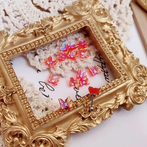 Detail of 3D colorful aurora butterfly ear studs and red heart barbell piercing jewelry