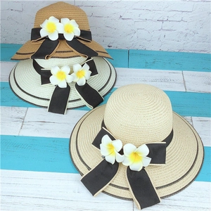 Détail de chapeaux de paille avec nœuds floraux sur une surface en bois nautique