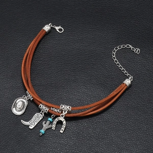 Detail of leather bracelet featuring Good Luck horseshoe and cowboy charms on black background