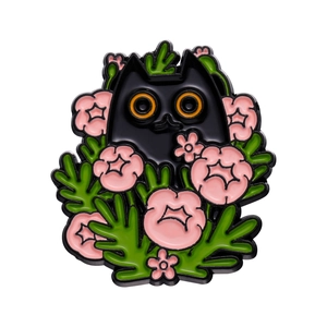 Macro shot of black cat enamel pin with pink flowers and green leaves on metal