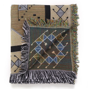 Detail of woven geometric blanket showing colorful tassels and reversible pattern texture