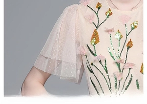 Detail of pink mesh sleeve with floral embroidery and sequins on the dress