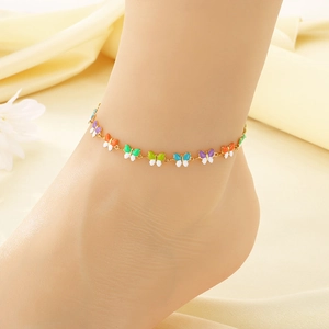 Golden chain anklet with colorful enamel butterfly pendants worn on a model's ankle