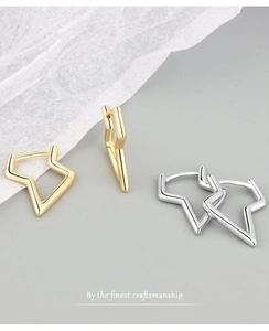 Detailed close-up of geometric star-shaped earrings in gold and silver finishes
