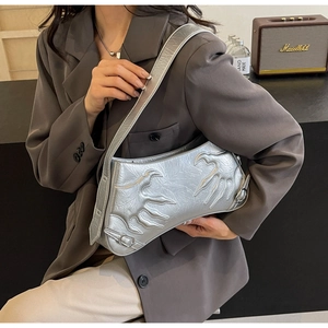Detail of silver metallic baguette bag featuring embossed flame patterns and buckle