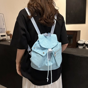 Close-up of light blue nylon backpack with drawstring flap closure on model in a cafe