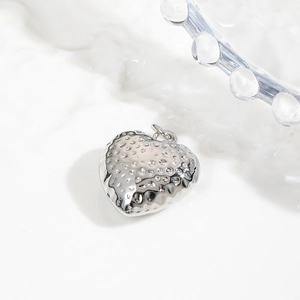 Detailed close-up of a silver heart pendant with unique hammered metal texture and glossy finish