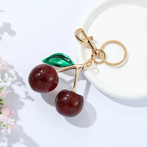 Sparkly dark red cherry keychain with green leaves and gold metal clip for bags
