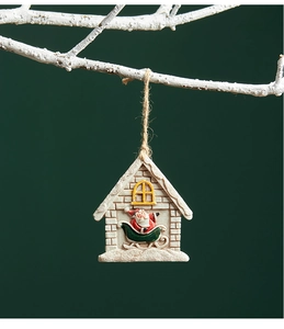 Close-up of resin Santa house ornament hanging on snow-dusted branches with rope
