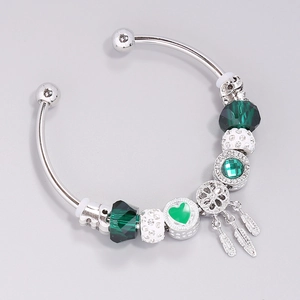 Silver open bangle with ocean blue glass beads, green crystal charms and feather pendants