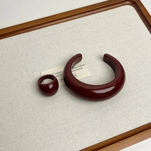 Macro view of polished deep red resin jewelry set including thick bangle and ring